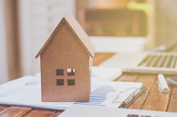 A small model of a house on a clipboard